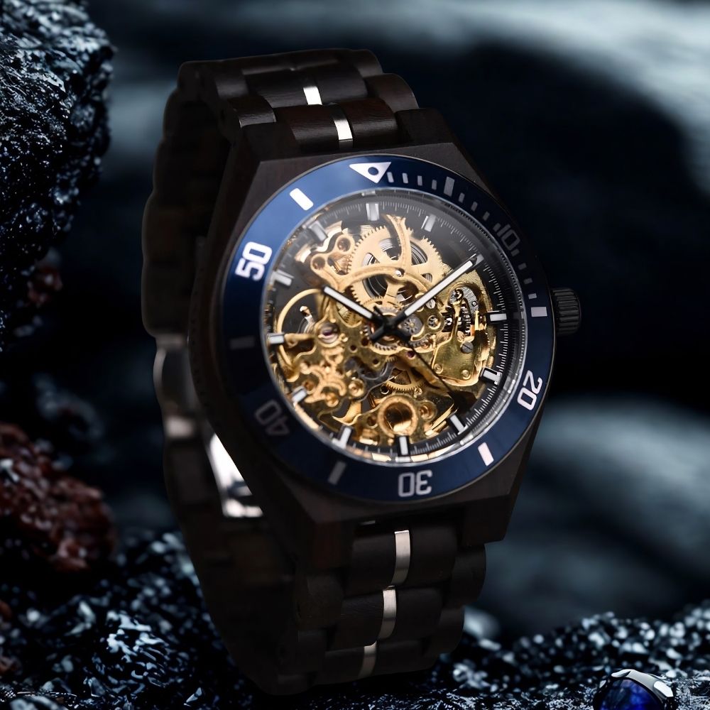 A luxury wood skeleton watch with a dark metallic case and band, featuring a blue bezel and a highly visible gold-toned mechanical movement through the dial, set against a dark, moody background.