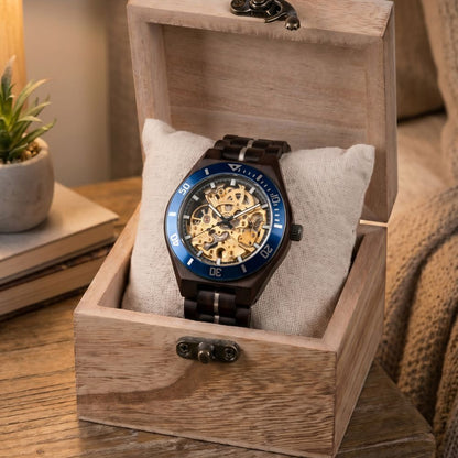 Watch with a blue and gold face in a wooden box on a wooden surface.