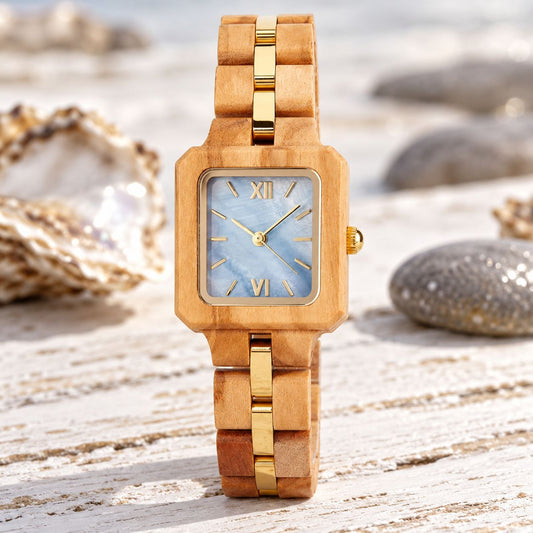 The Blue Pearl women's olive wood watch standing among oyster shells and pebbles