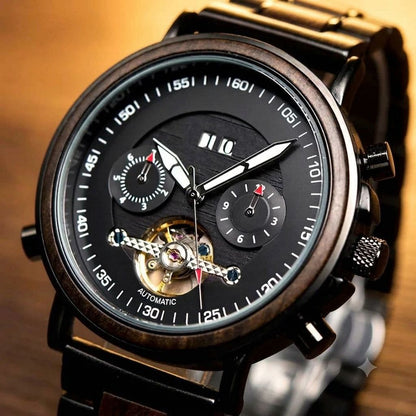 A close-up of a luxury automatic watch with a black dial, white hands, a wood-grain bezel, and a visible gold-tone mechanical movement with a skeletonized lower dial.